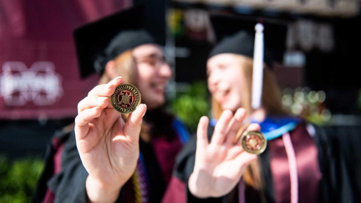 Photo of MSU Graduates holding coins
