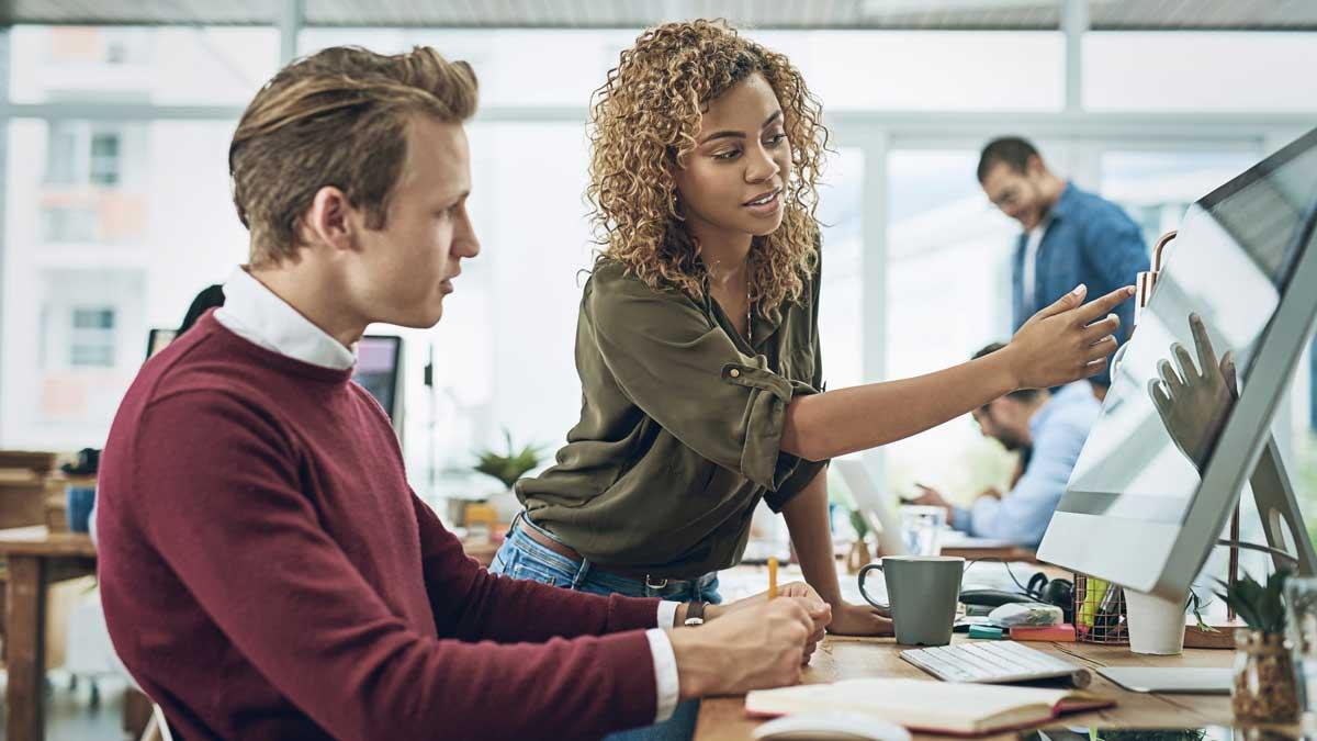 Workplace setting of a manager showing an employee something on a computer screen