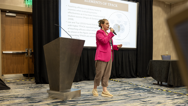 Dr. Kenna Vowell speaking in front of a podium and screen